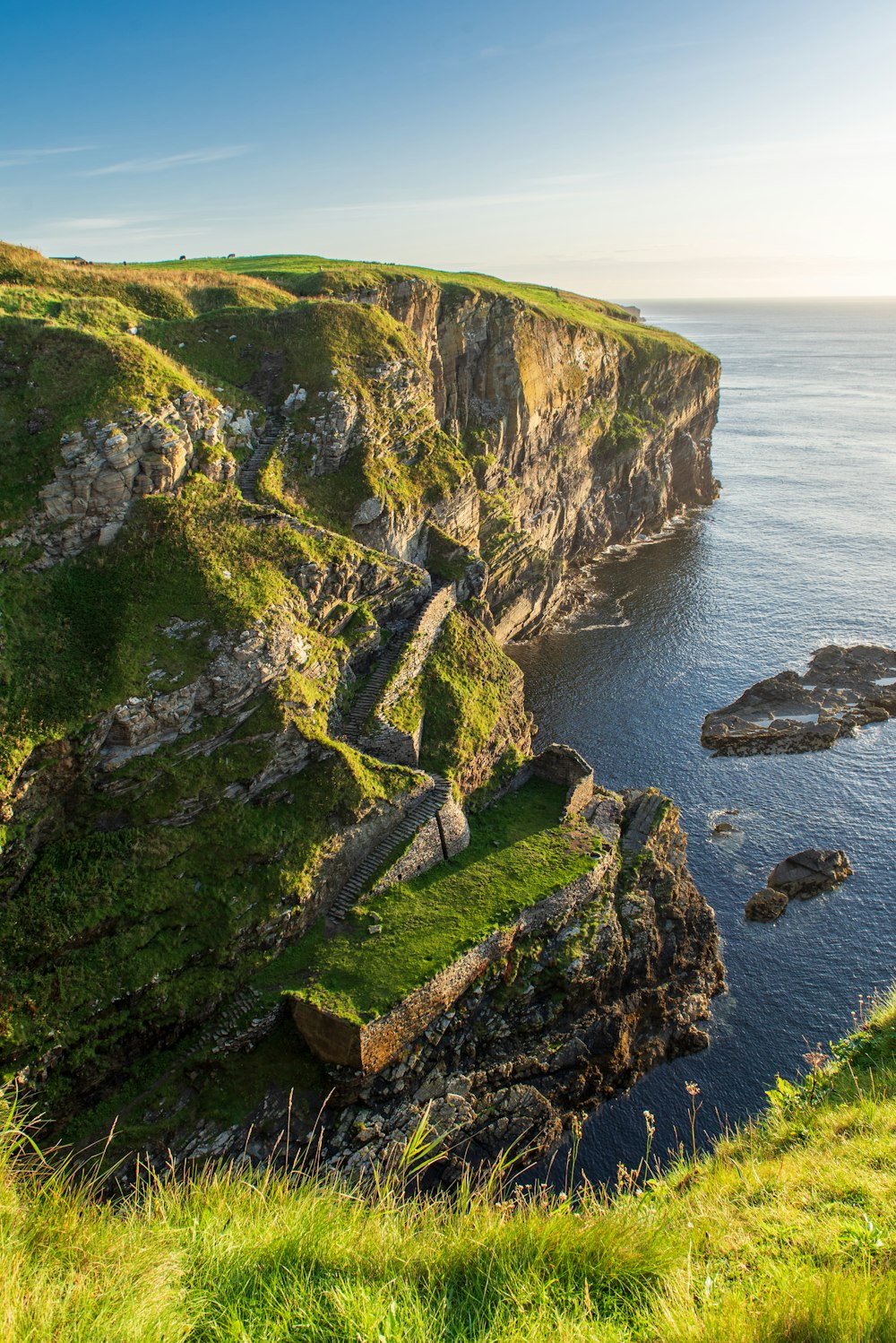 green and brown rock formation beside body of water during daytime