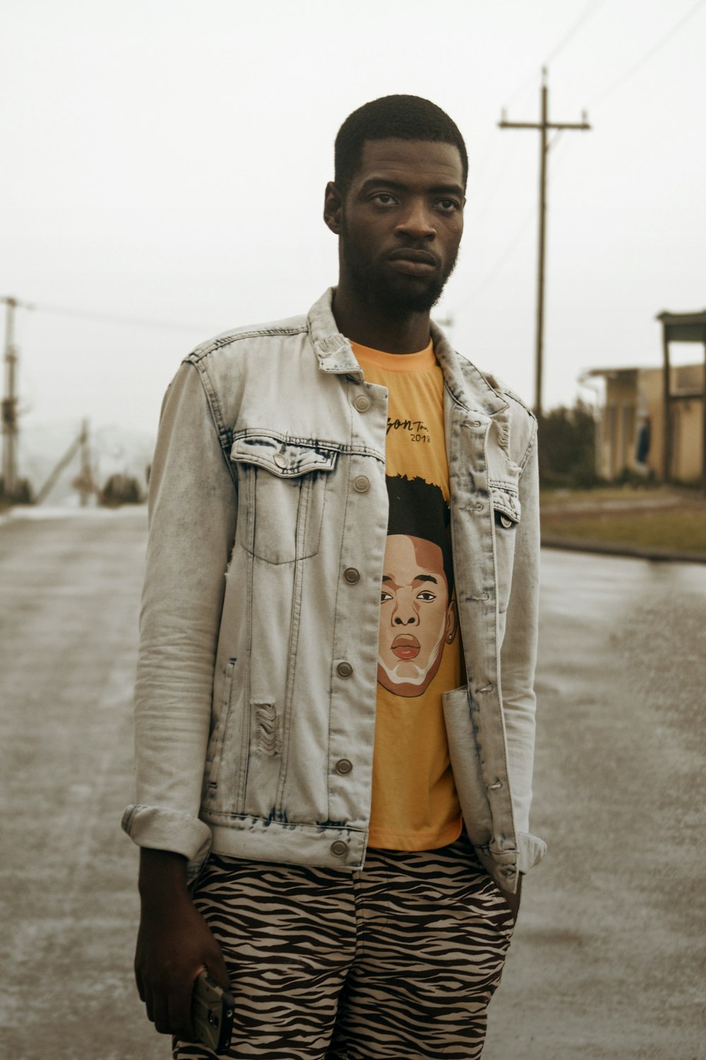 man in gray denim jacket standing on road during daytime