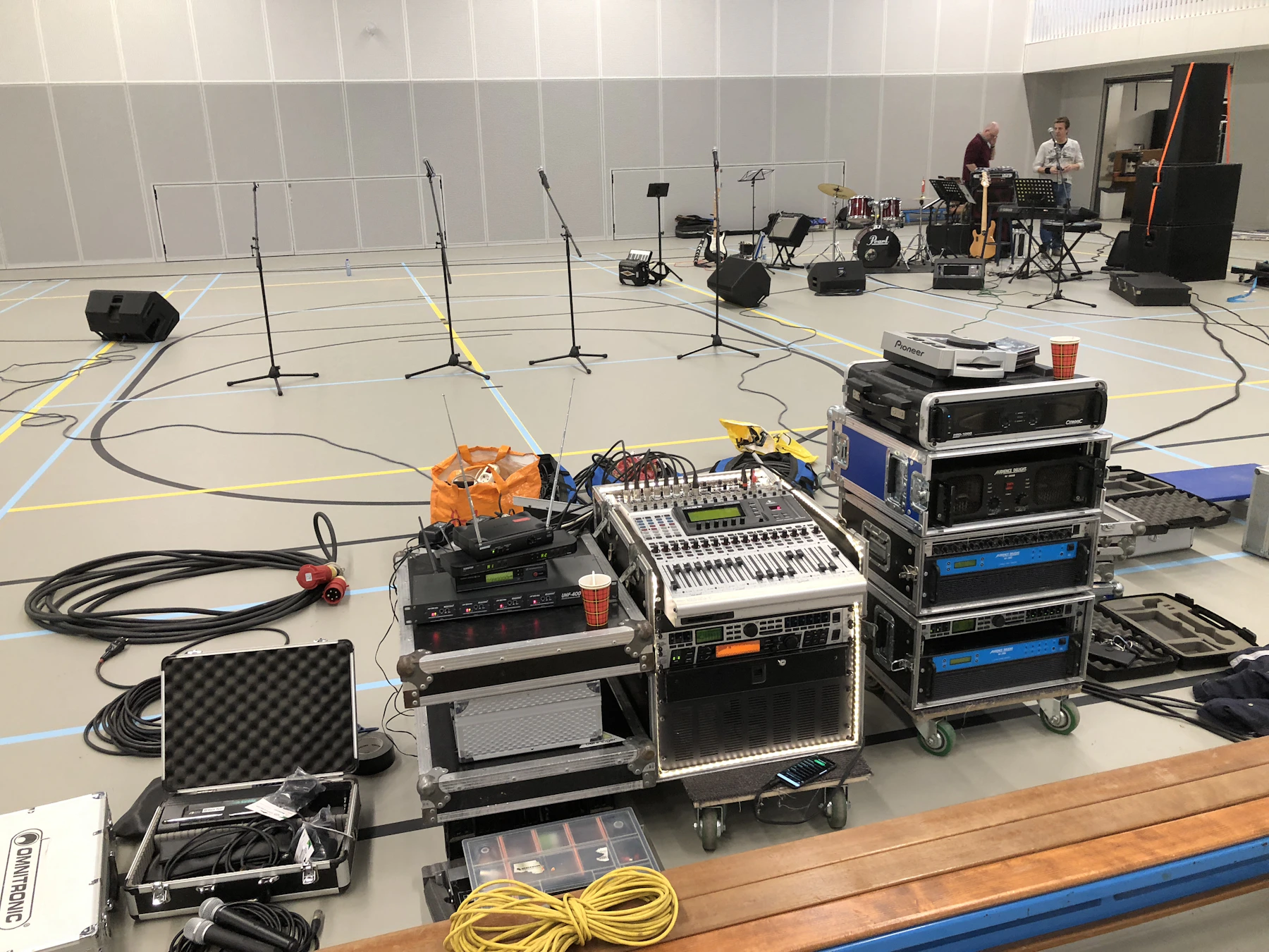 Palco allestito con diffusori, monitor, microfoni, mixer e cablaggi audio