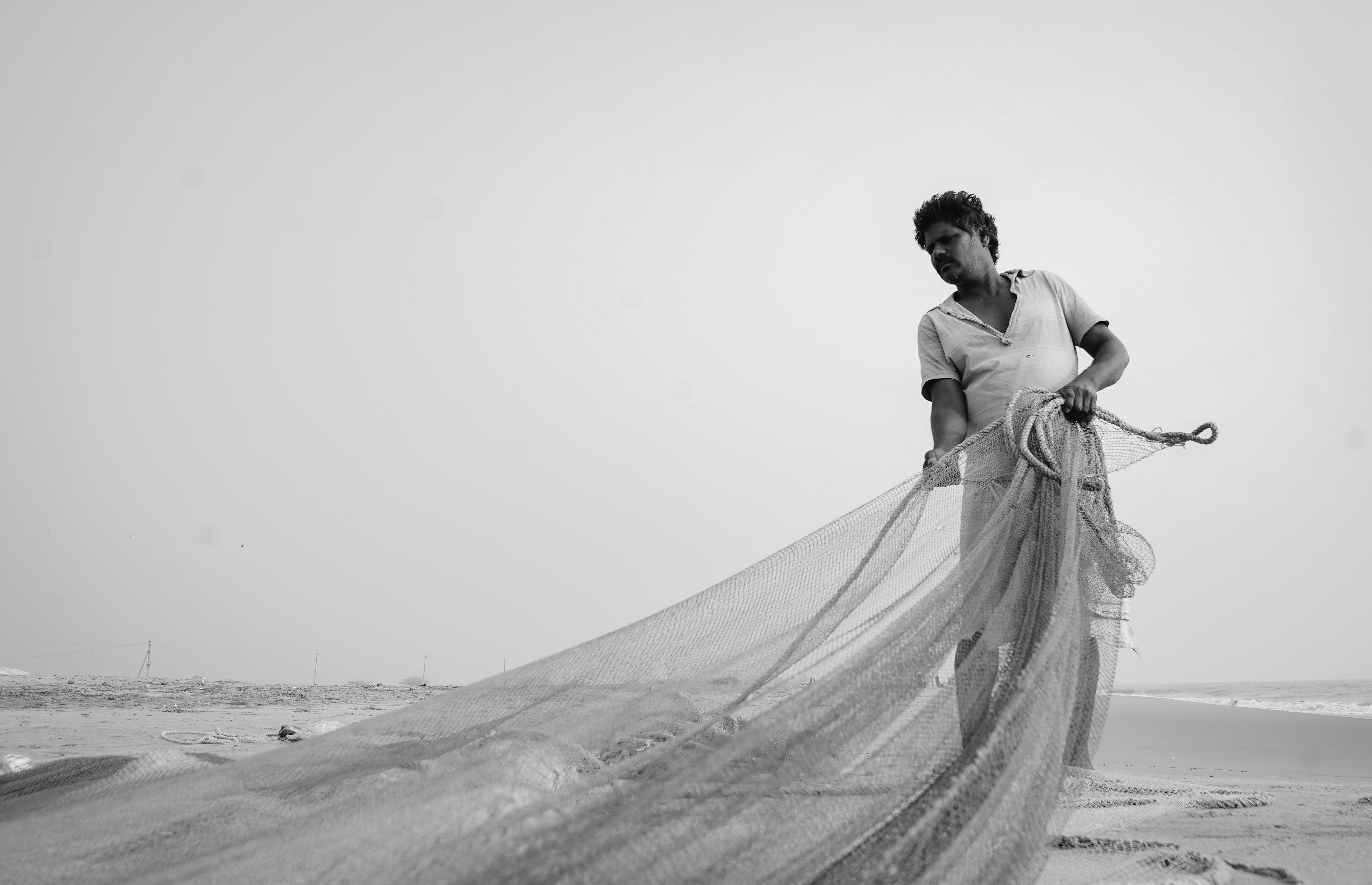 Ein Mann, der auf einem Strand steht und ein Netz hält