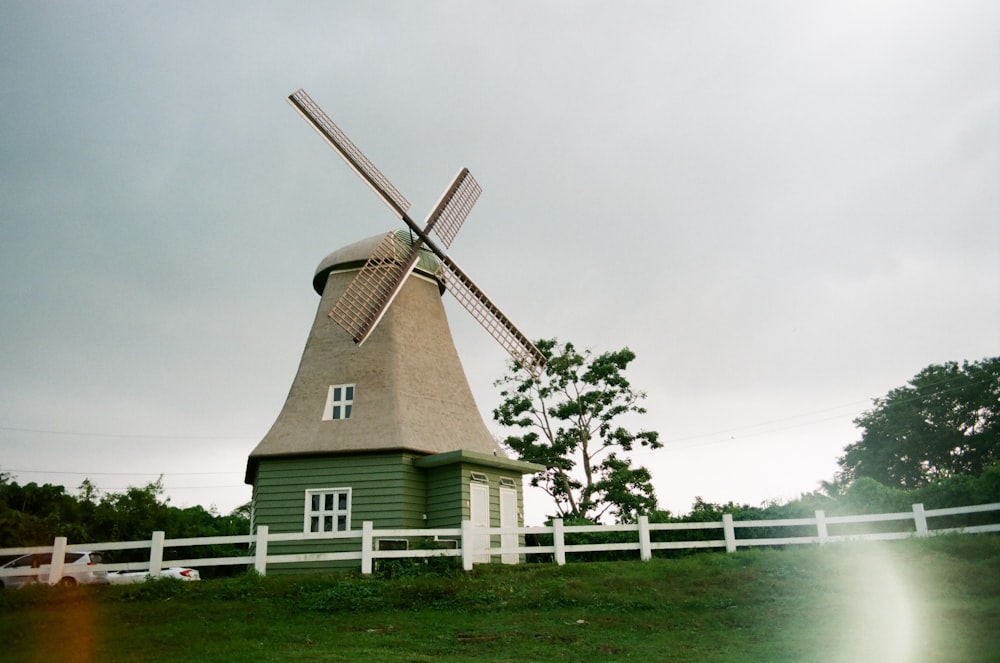 brown and white windmill near green tree under white sky during daytime