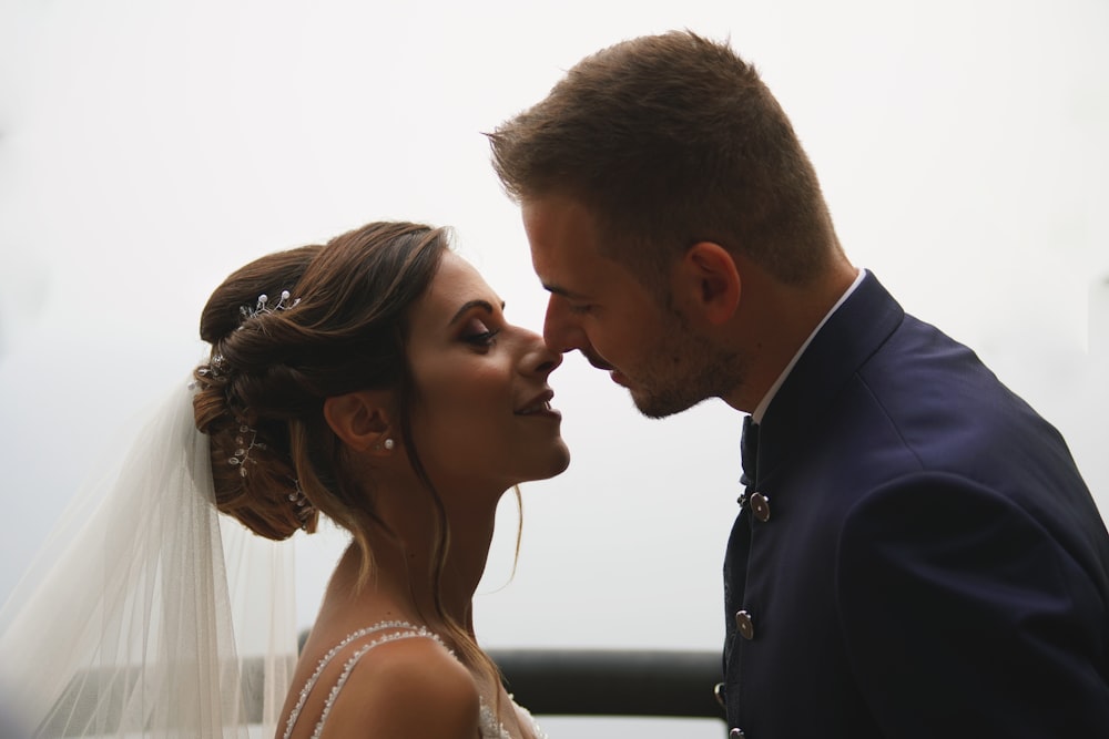 man in black suit kissing woman in white dress