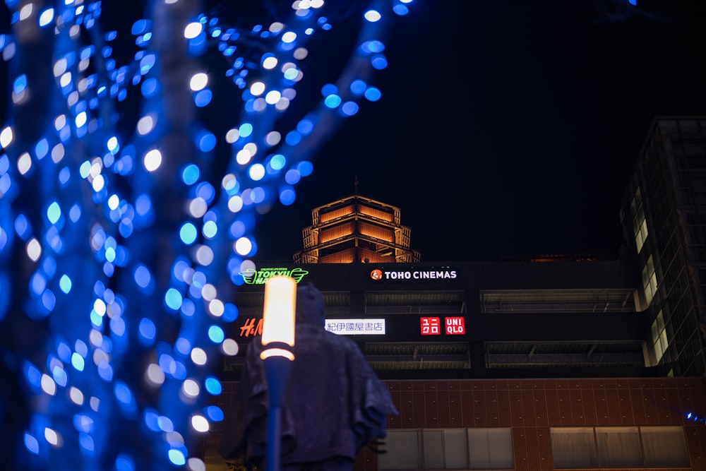 man in black coat standing near blue lights during nighttime