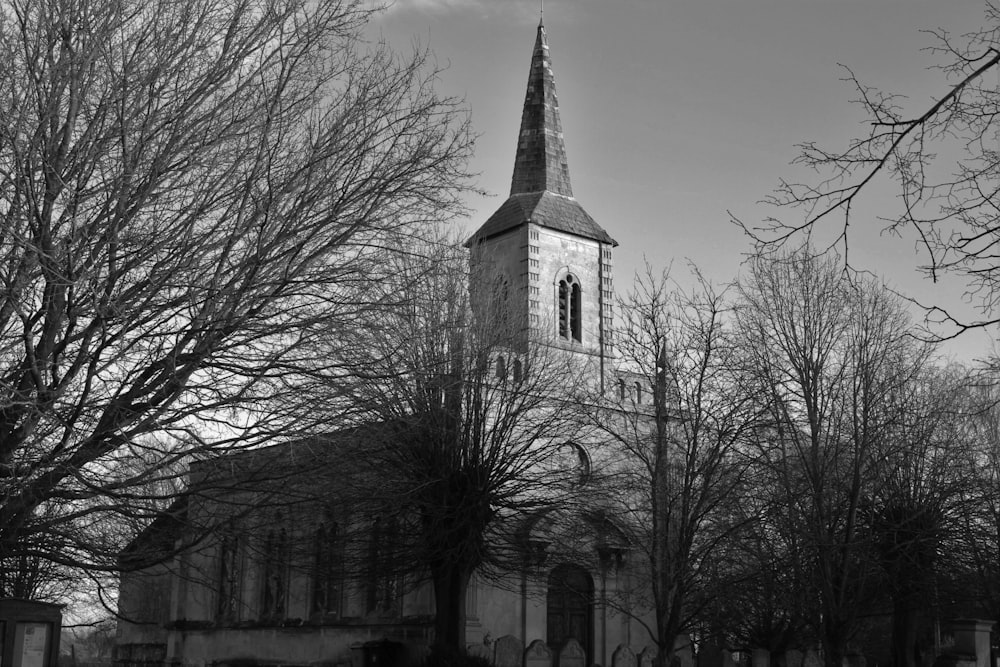 grayscale photo of church near bare trees