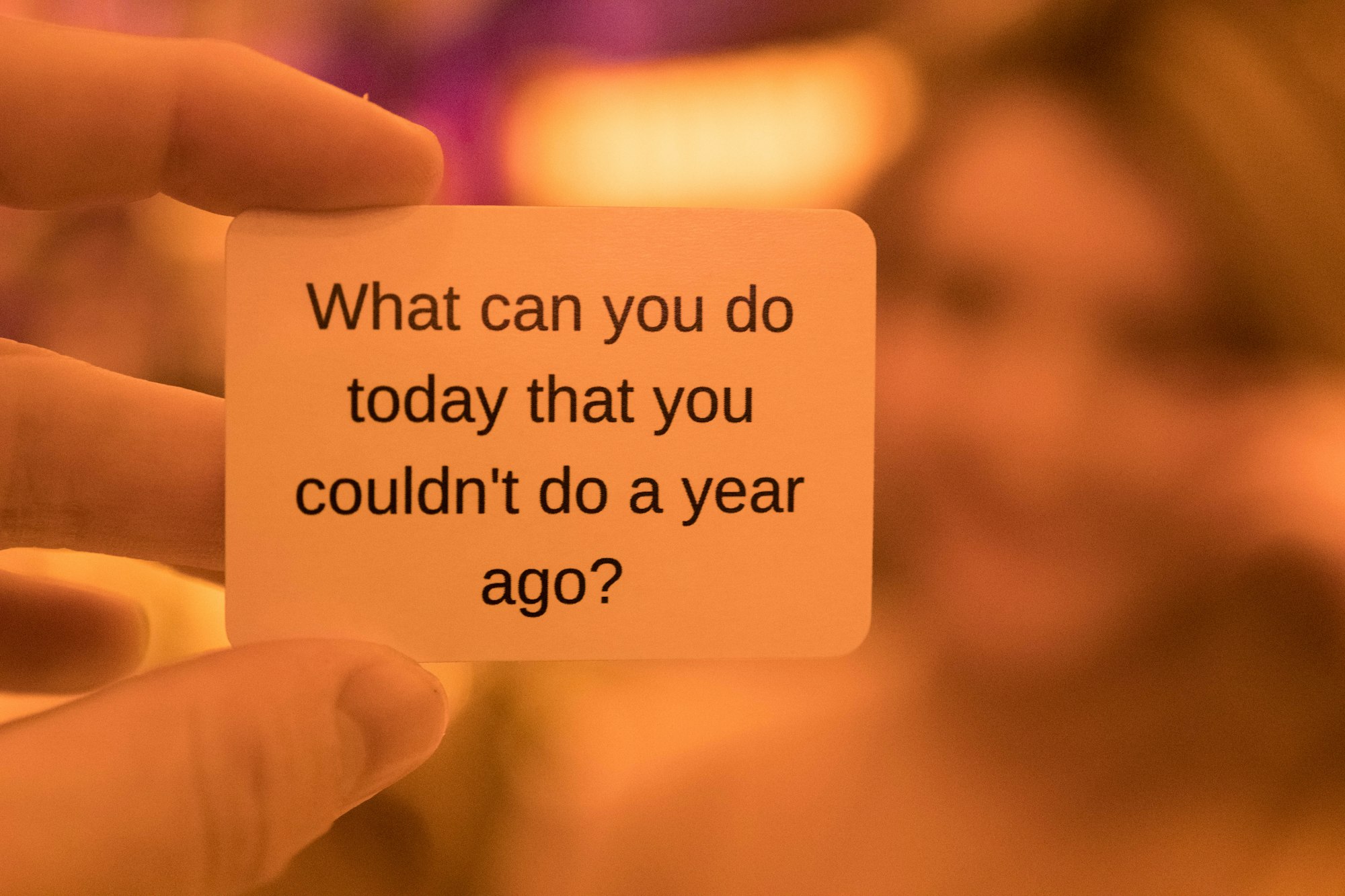 Fingers hold a small card that says, "What can you do today that you couldn't do a year ago?"