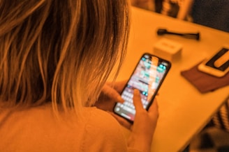 woman in white shirt holding black iphone 4