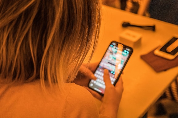 woman in white shirt holding black iphone 4