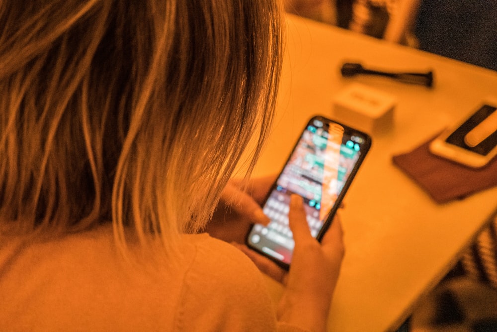 woman in white shirt holding black iphone 4