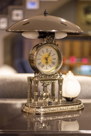 A vintage brass clock with intricate details resting on a wooden table.