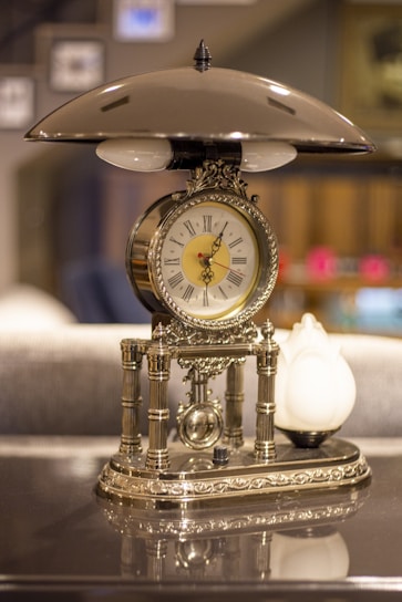 An elegant table clock placed on a stylish wooden desk.