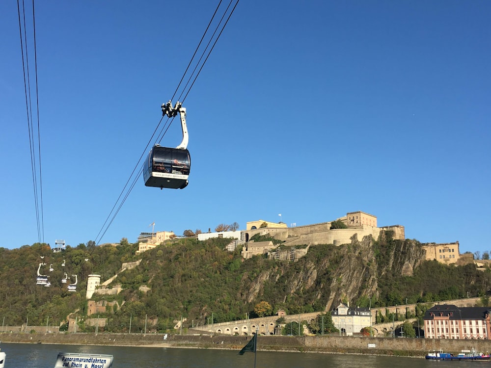 Teleférico negro sobre árboles y edificios verdes durante el día