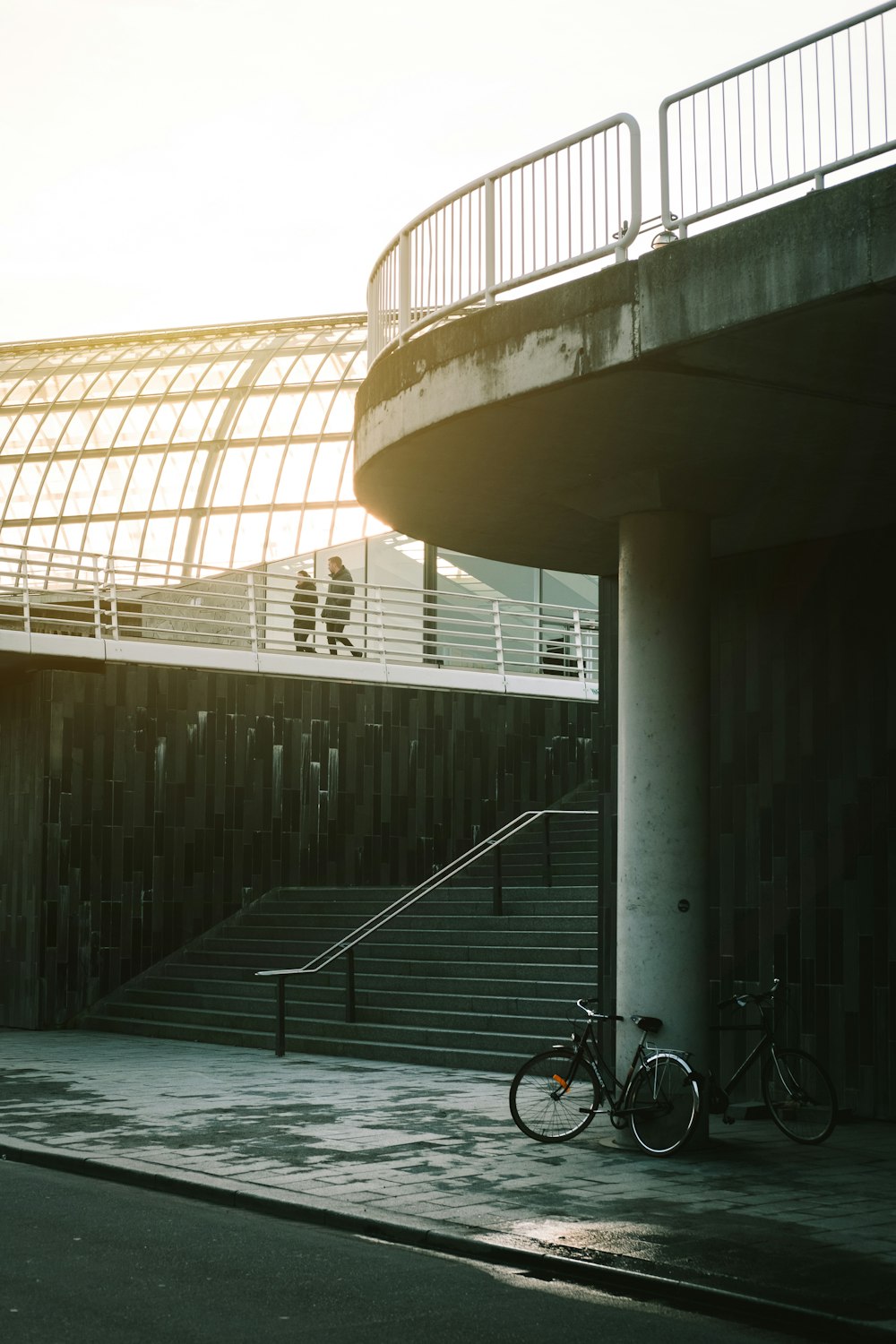 白いコンクリートの建物の脇に停められた黒い自転車