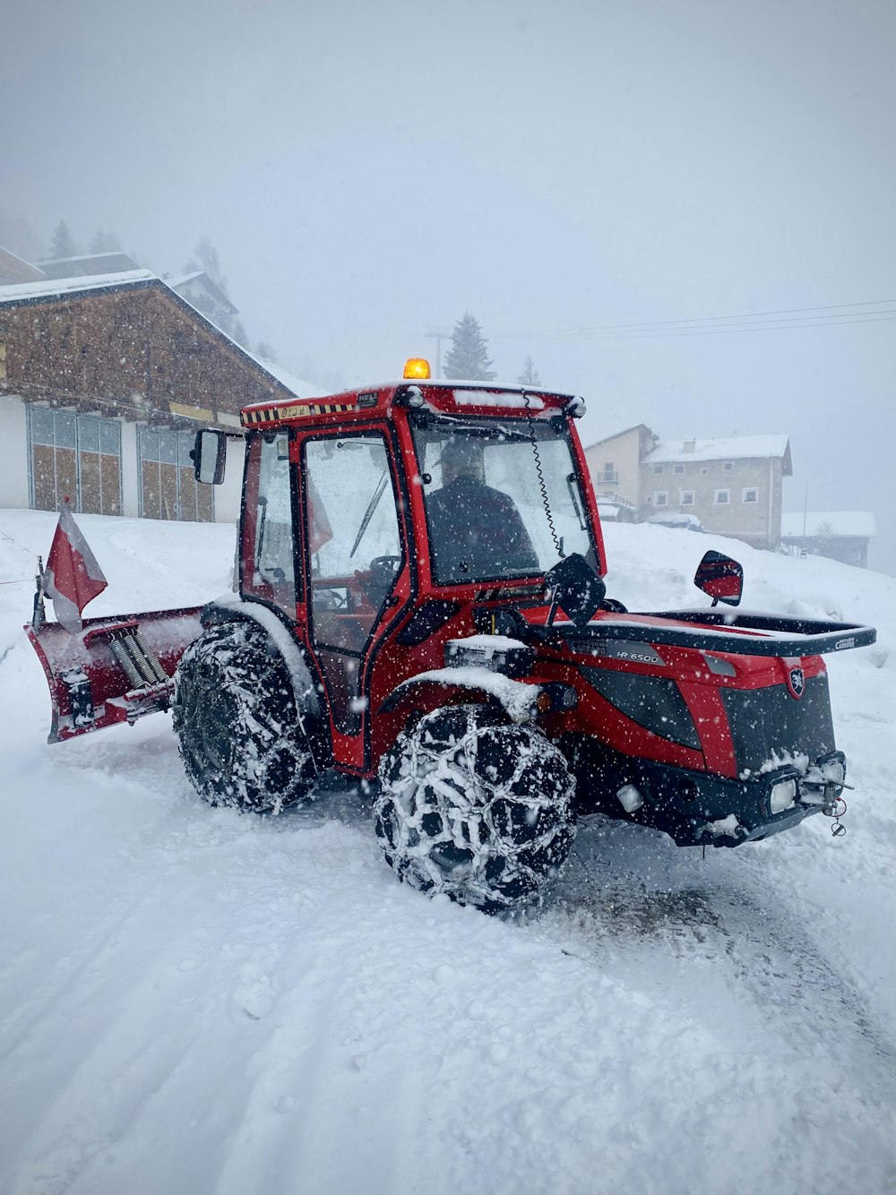 昼間は雪に覆われた地面を走る赤と黒のトラクター