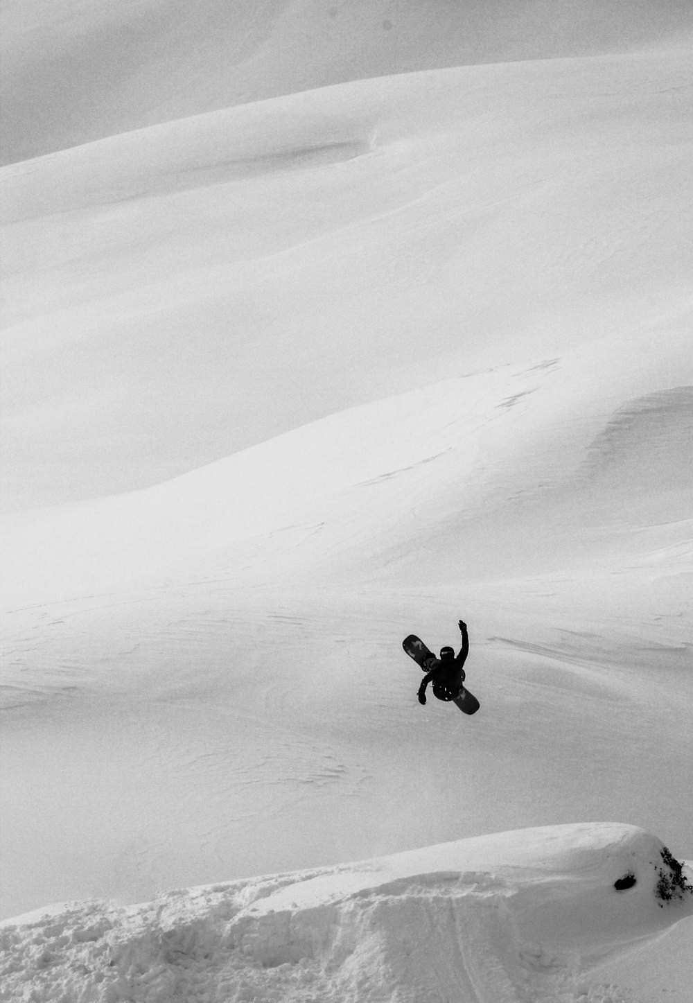 Person in schwarzer Jacke und Hose, die tagsüber auf schneebedecktem Boden geht