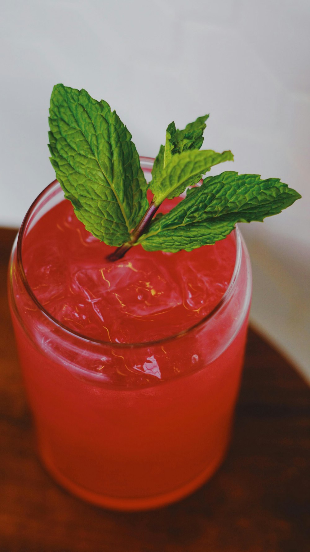 red liquid in clear drinking glass with green leaves