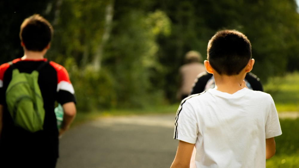 man in white crew neck t-shirt standing on road during daytime