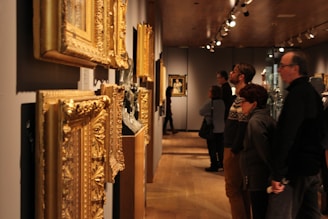 A group of visitors admiring paintings in a cozy gallery space with wooden floors.