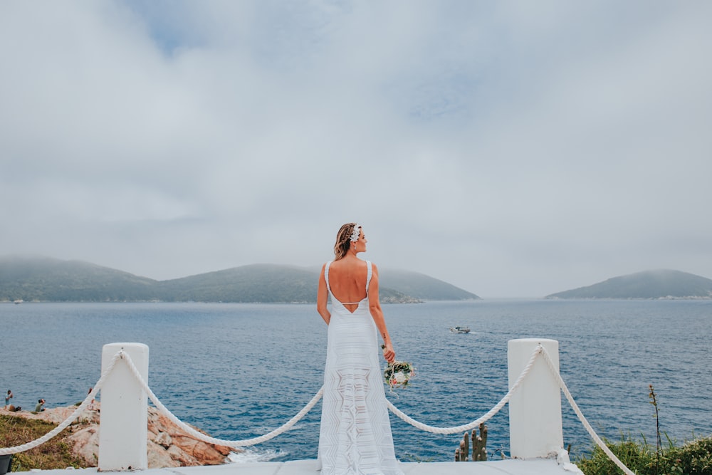 woman in white dress standing on white wooden dock during daytime