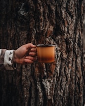 person holding clear glass mug with brown liquid