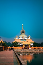 people walking on street near white and gold temple under blue sky during daytime