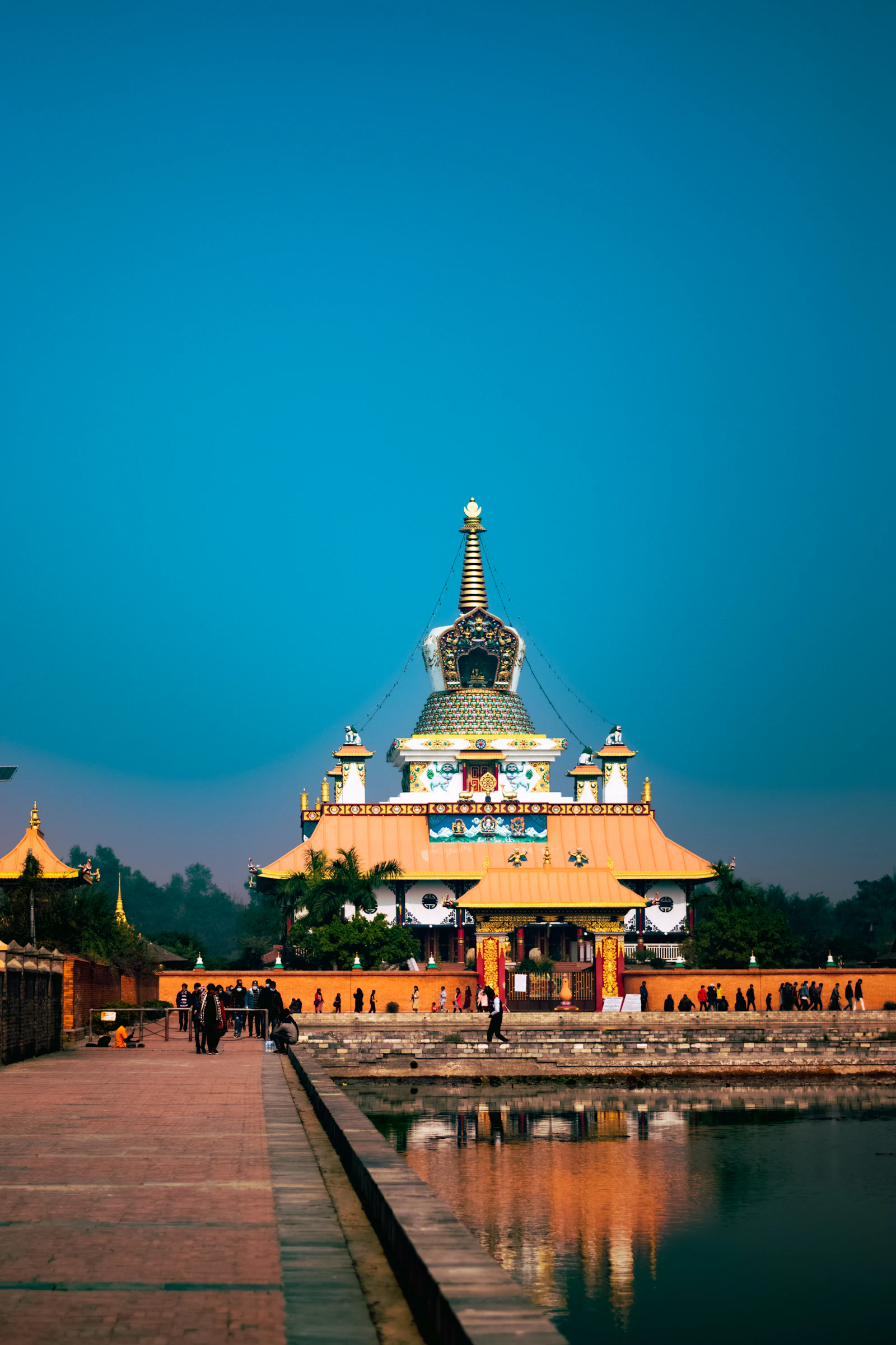 People walking near a white and gold temple in Lumbini Nepal
