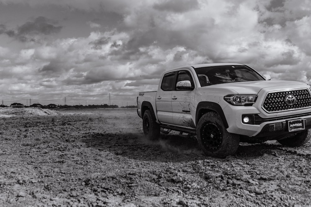 white crew cab pickup truck on gray sand under white clouds during daytime