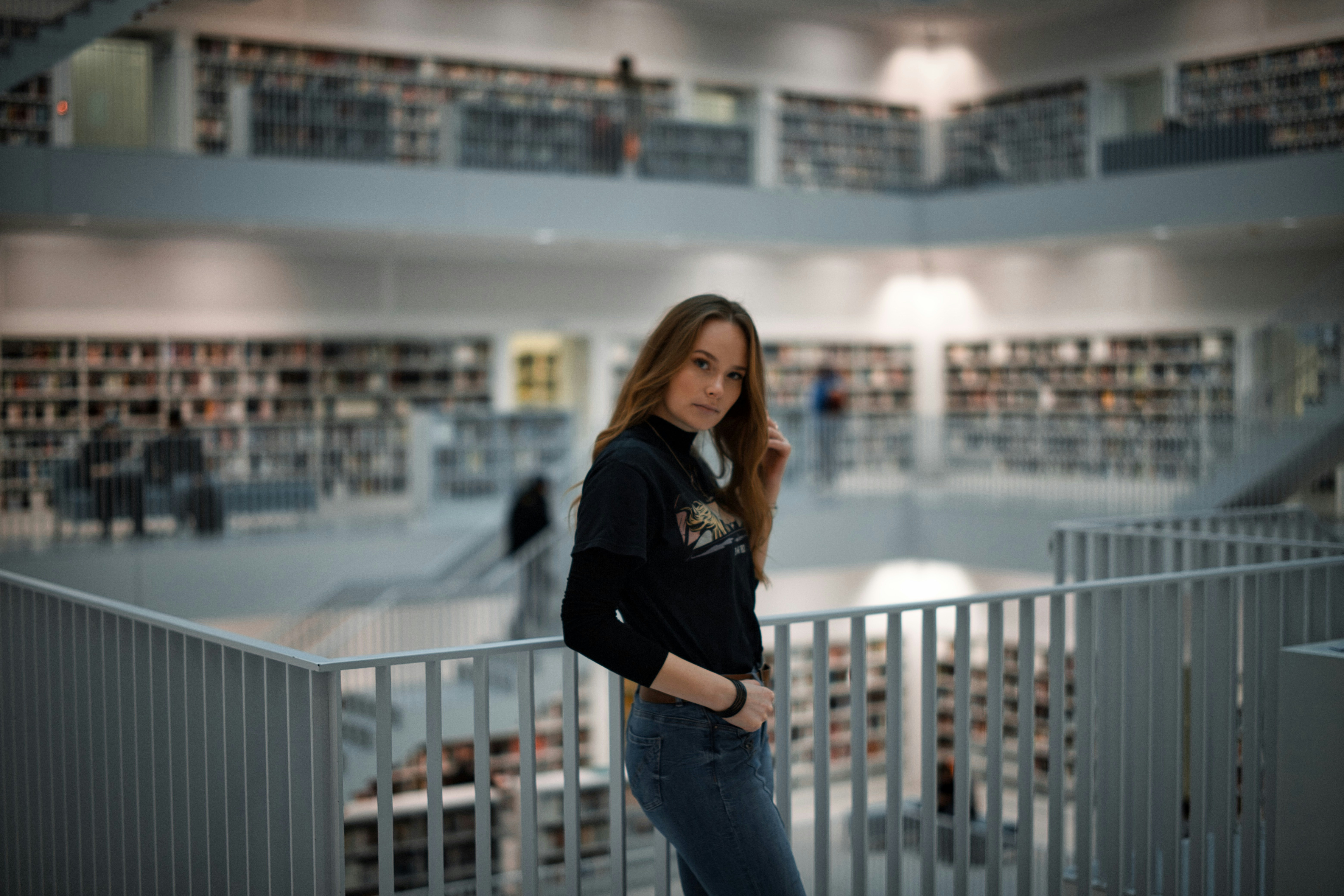 woman in black shirt and blue denim jeans standing on balcony during daytime