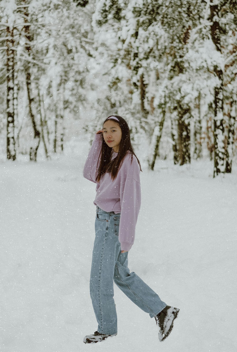 woman in pink long sleeve shirt and blue denim jeans standing on snow covered ground during