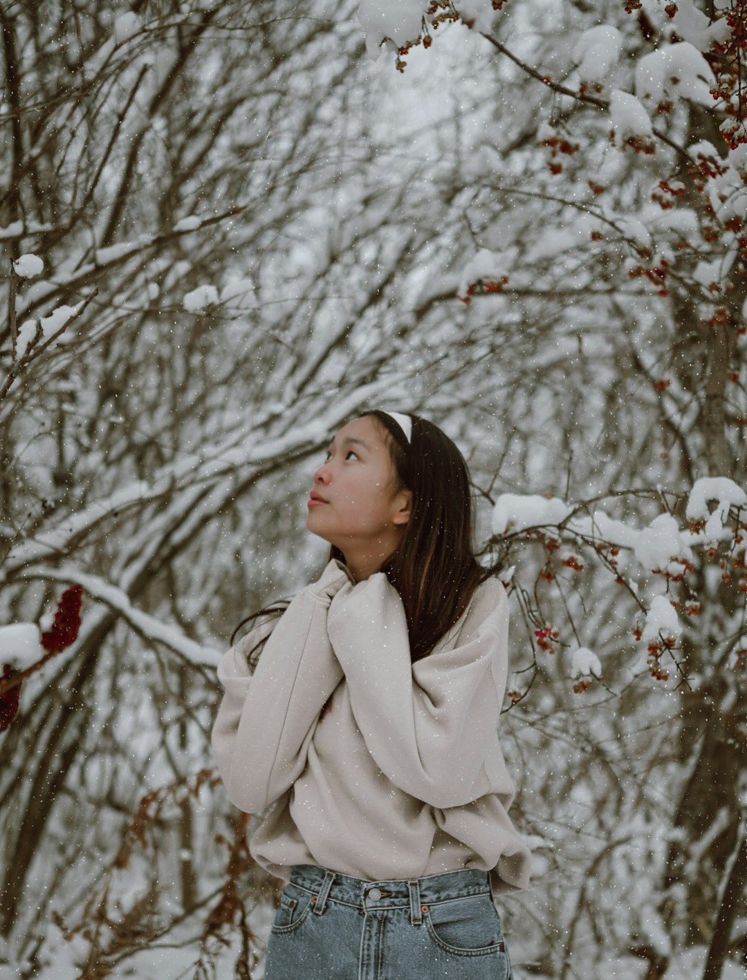 woman in beige coat standing near bare trees during daytime