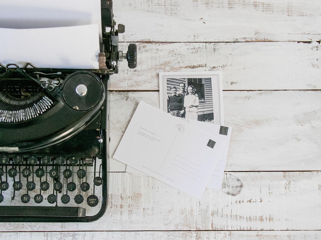 black typewriter beside white printer paper