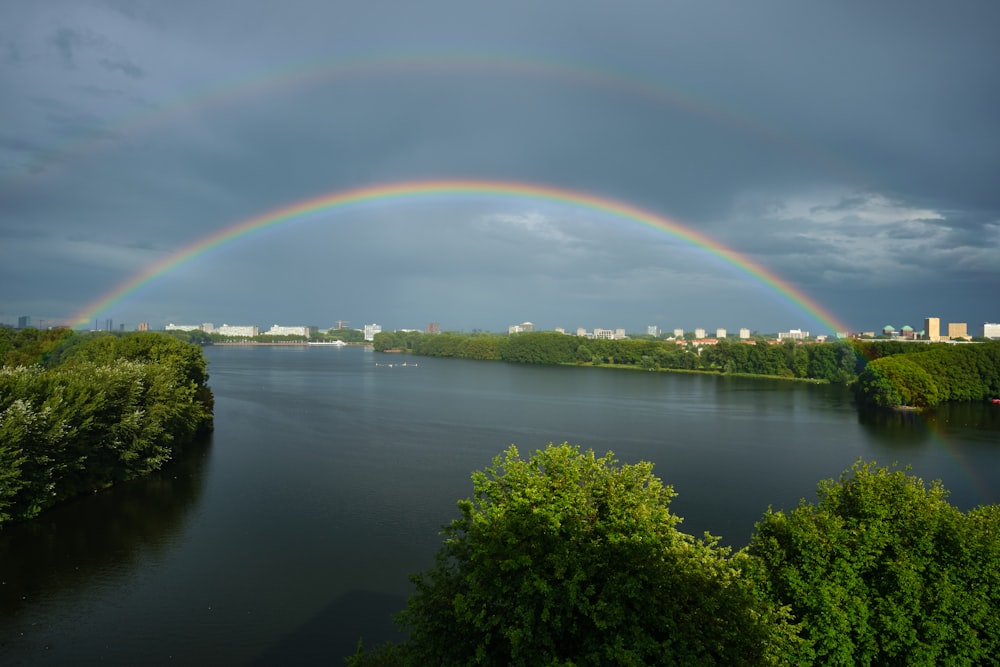 rainbow over green trees and lake