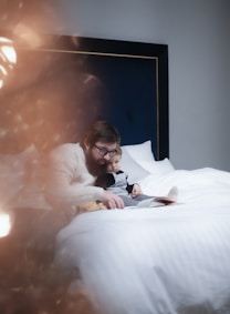man in black suit lying on bed beside woman in white long sleeve shirt