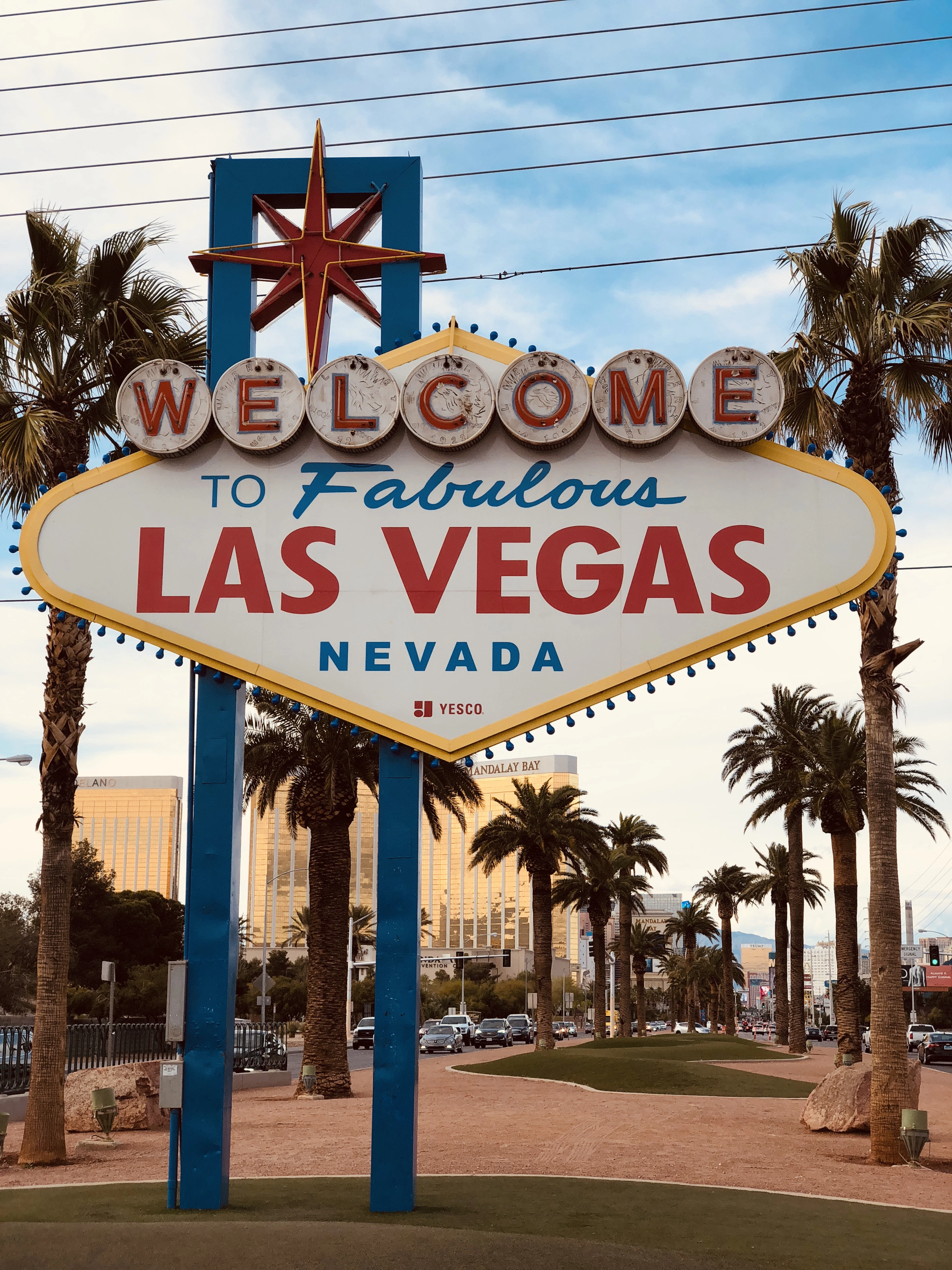 The Welcome to Fabulous Las Vegas sign in daylight, with Strip hotels and palm trees behind it.
