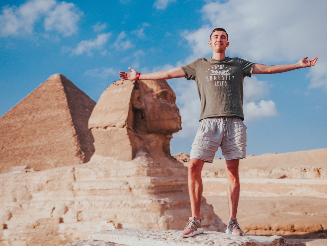 man in gray crew neck t-shirt and white shorts standing on brown rock formation during