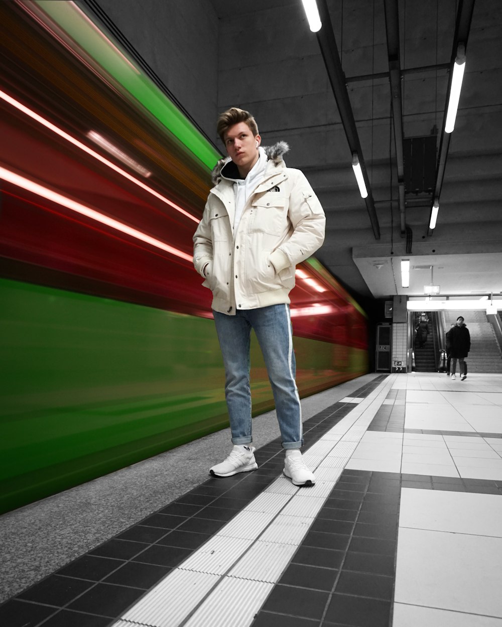 man in white zip up jacket and blue denim jeans standing on white floor tiles