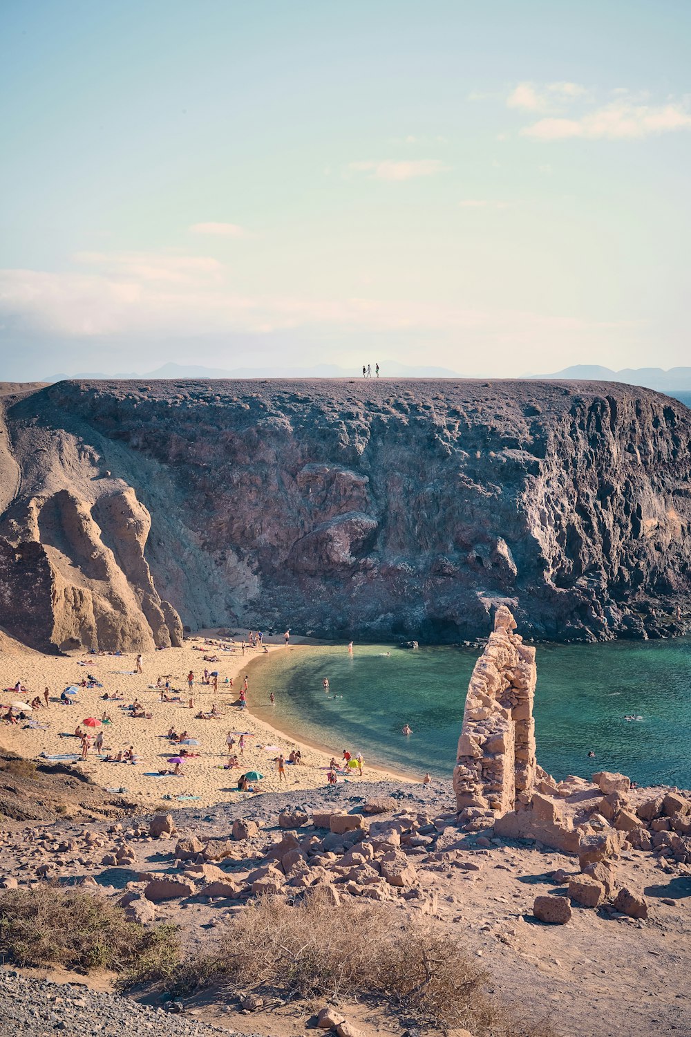 people on beach near brown rock formation during daytime