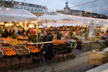 Golden afternoon light casts long shadows over vibrant stalls filled with fresh fruits and vegetables.