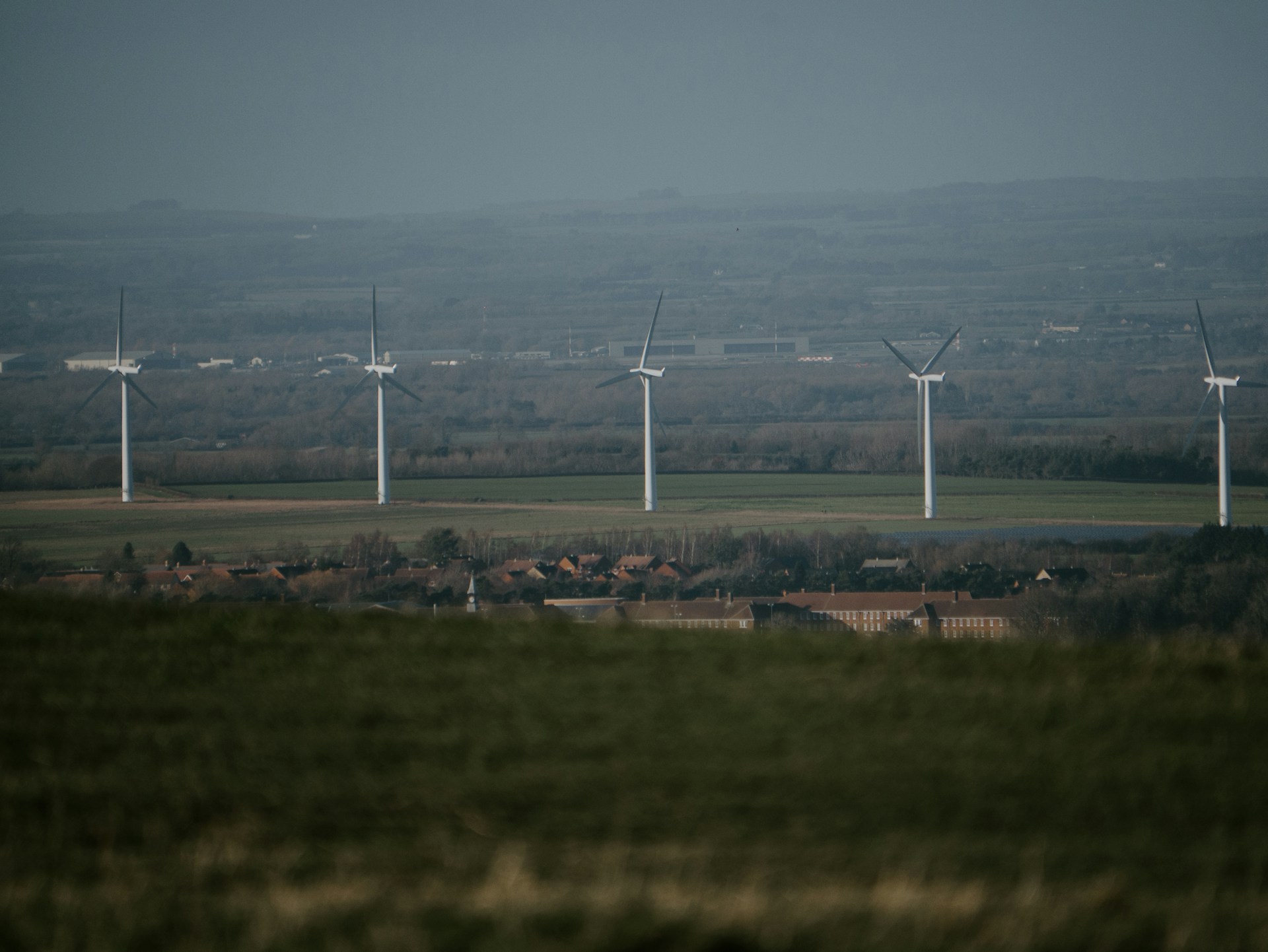 white wind turbines on green grass field under blue sky during daytime