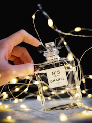person holding clear glass perfume bottle