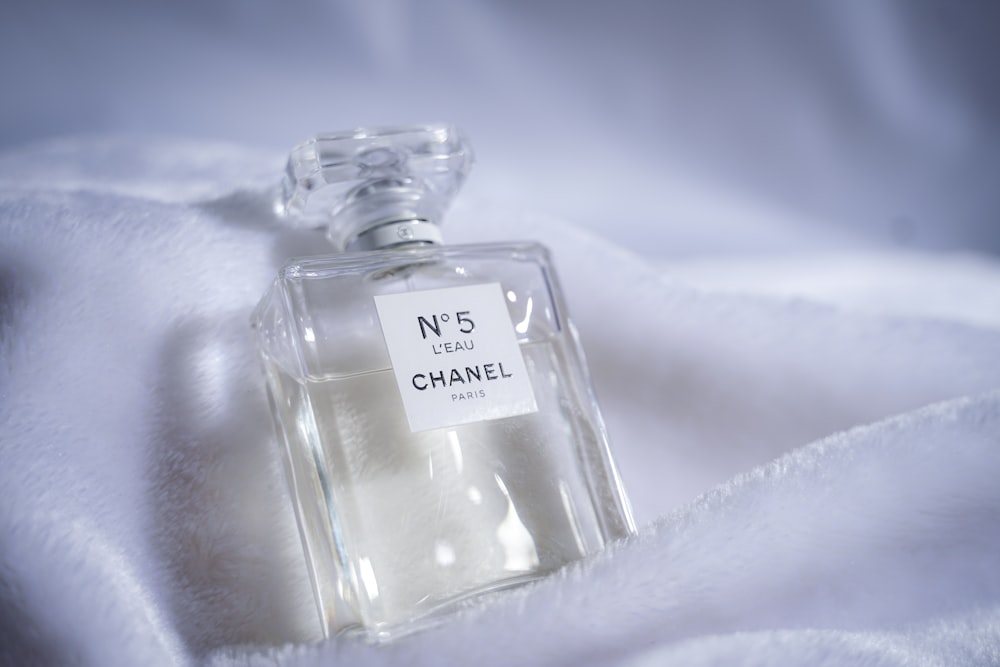 clear glass perfume bottle on white textile