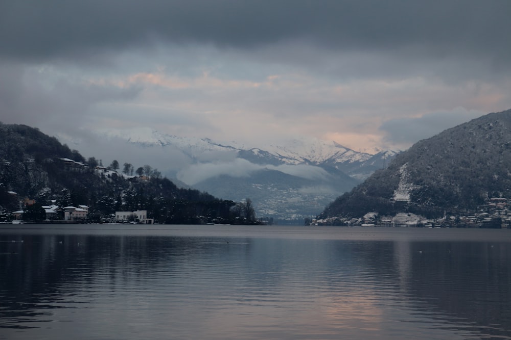 body of water near mountain under cloudy sky during daytime