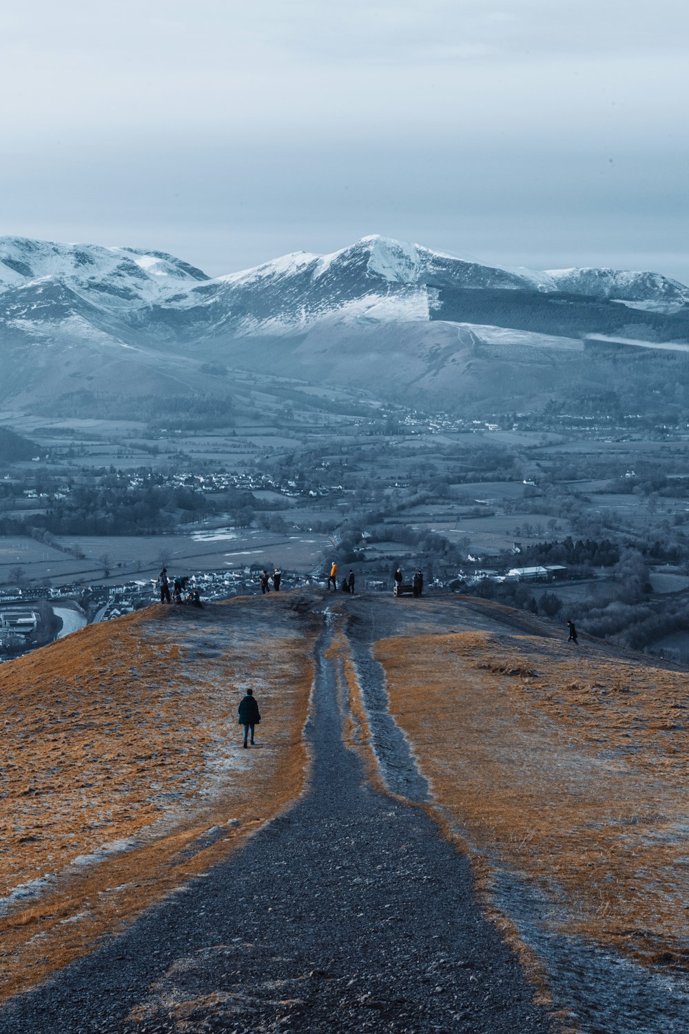 Persone che camminano sul campo marrone vicino alla montagna coperta di neve durante il giorno