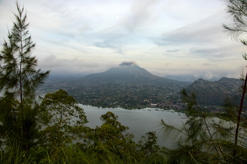 green mountain near body of water under white clouds during daytime
