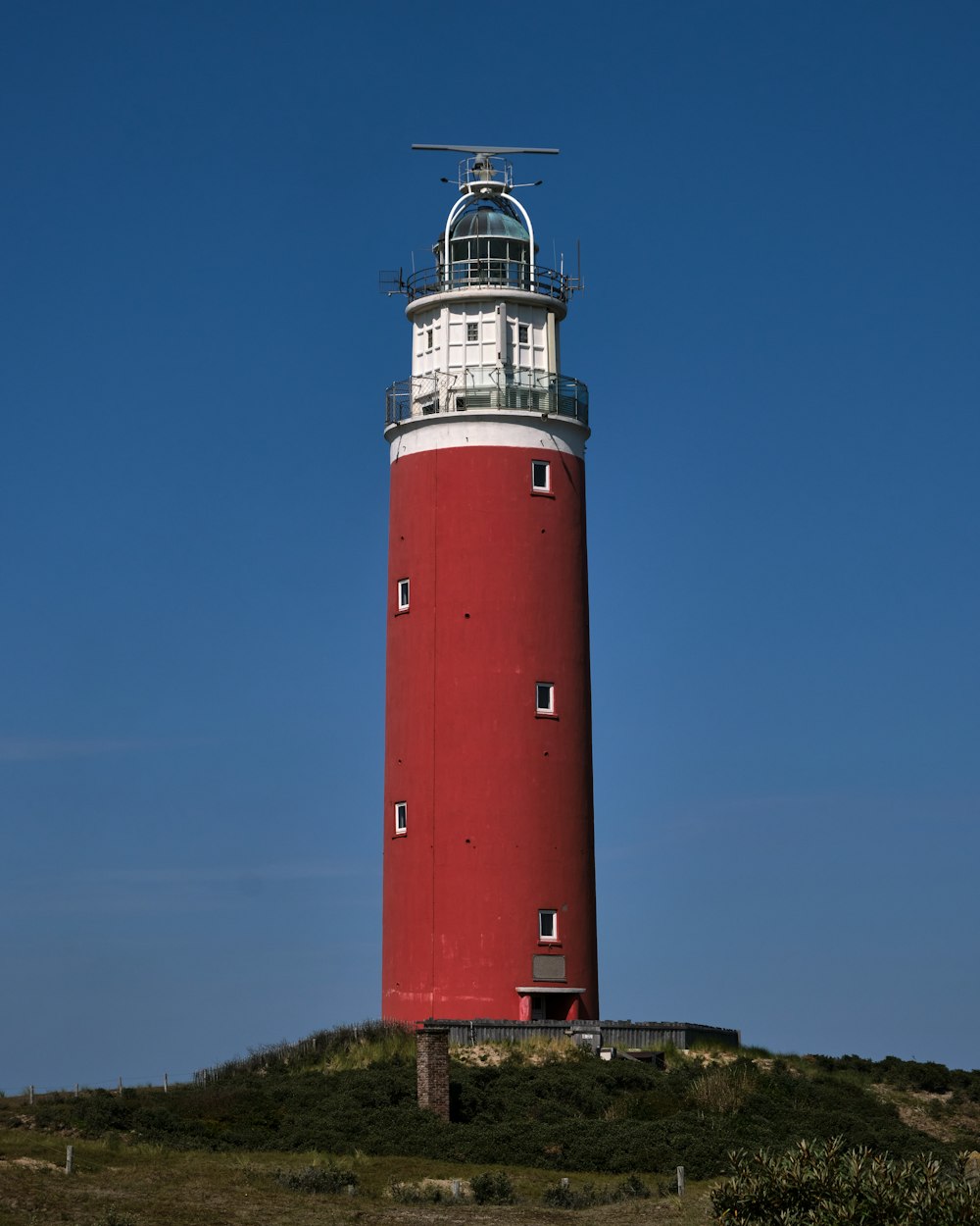 a red and white lighthouse on top of a hill