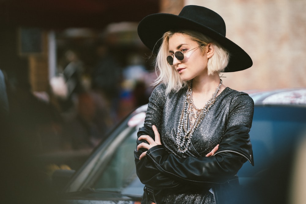 woman in black long sleeve shirt and black hat sitting on black car