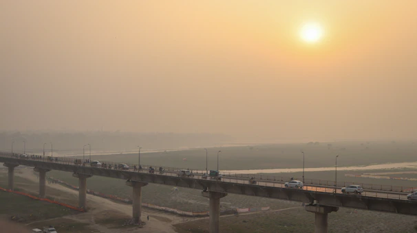 A wide shot of a large infrastructure bridge spanning a river with vehicles moving across under a clear sky.