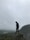 man in black jacket standing on rock formation during foggy weather
