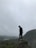 man in black jacket standing on rock formation during foggy weather