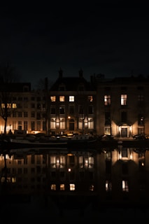 Night view from the apartment window overlooking the illuminated Navigli canals and city lights.