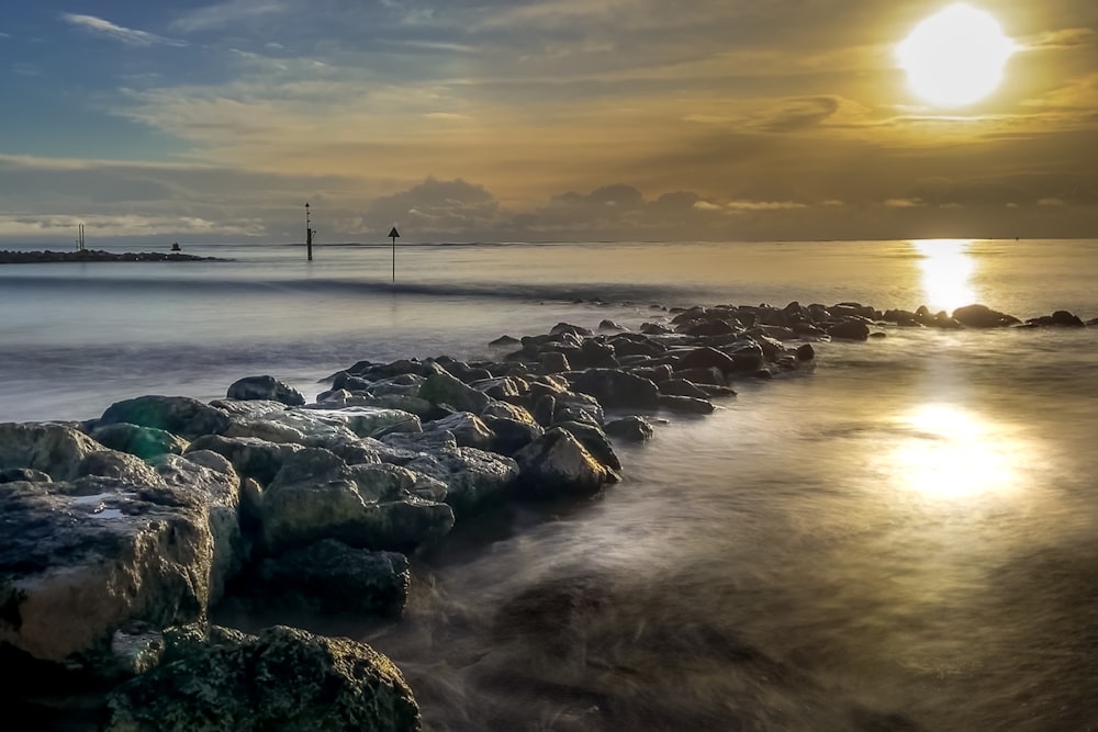 gray rocks on seashore during sunset